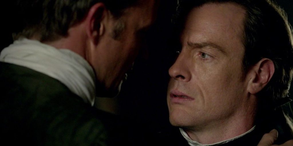 Flint and Thomas looking into each other's eyes intensely as they lean in for a kiss.