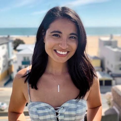 Olivie smiling at the camera with a beach in the background