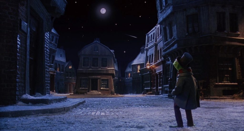 Movie still from A Muppet Christmas Carol, showing the snowy streets of London, and Kermit staring at the moon.