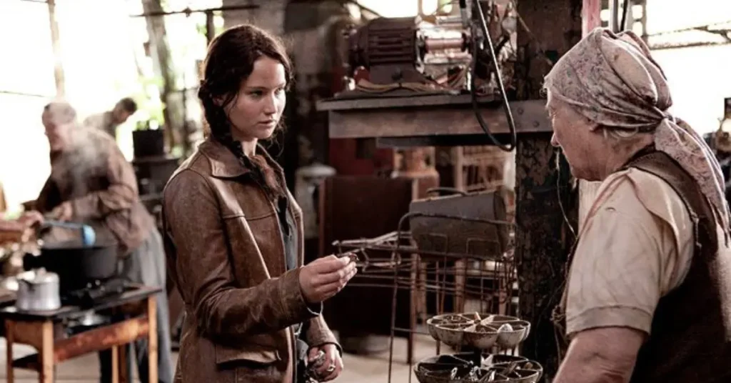 Katniss is trading for a pin from an older woman in a run-down market
