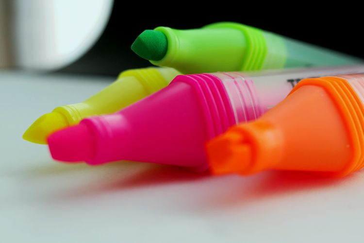four highlighters without caps laying in a pile on the table.
