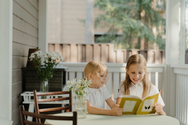 two girls sitting outside looking at a book by T. S. Eliot