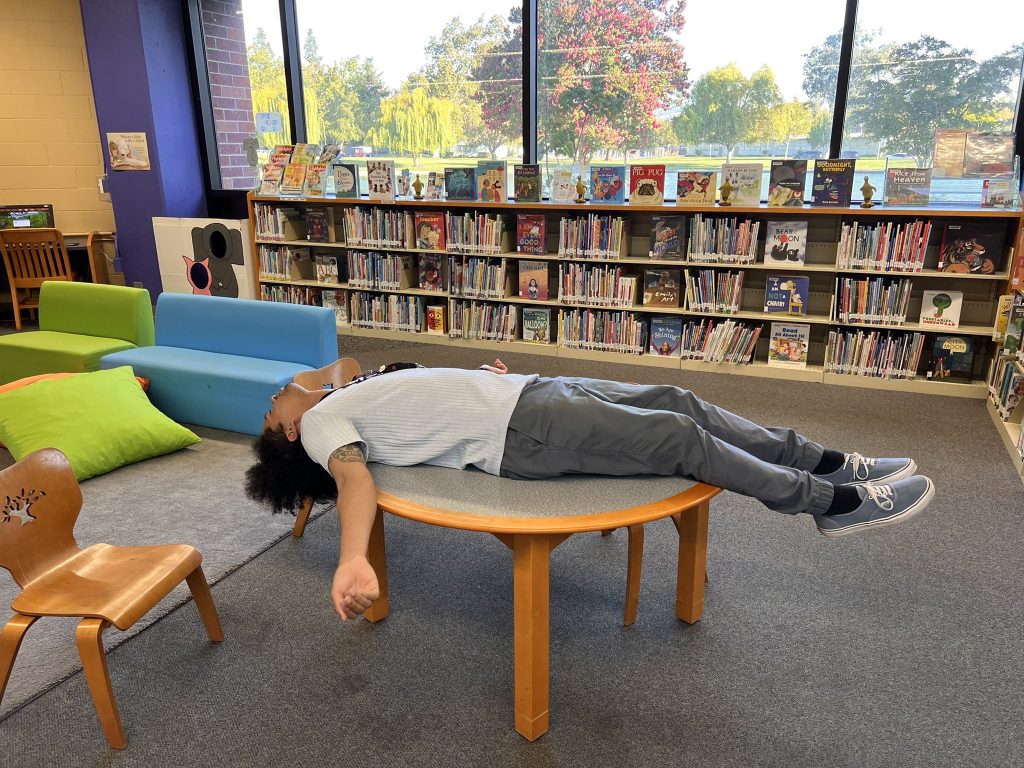 Mychal in a library lying on a table