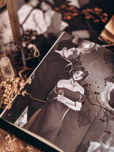 Image provided by Bookstagrammer Steph of an open book with two pages filled with a monochromatic art of a man and a woman dressed in fancy clothes.