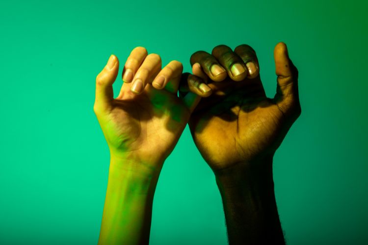 Two hands gently linked by their pinky fingers, symbolizing a delicate promise or connection.