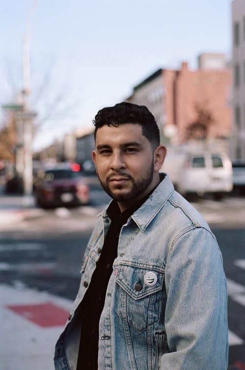 Ruben Reyes Jr. staring at the camera while standing outside in a city.