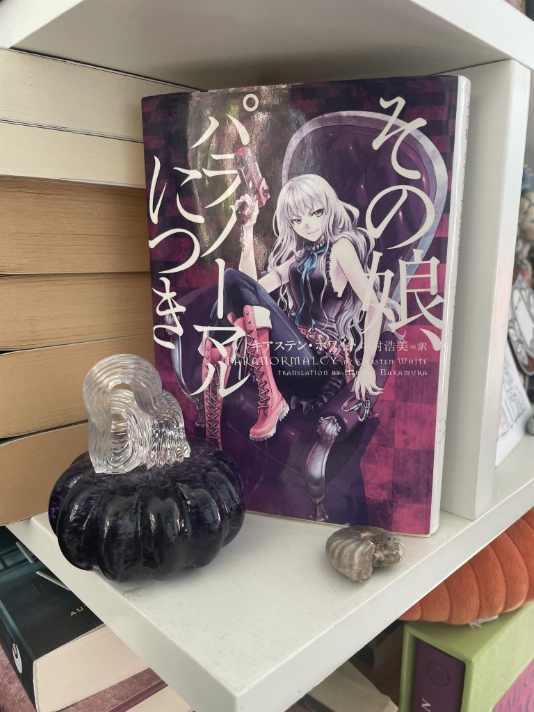 Image of Kiersten White's first book, Paranormalcy, on her bookshelf next to her glass trinkets and a small shell.