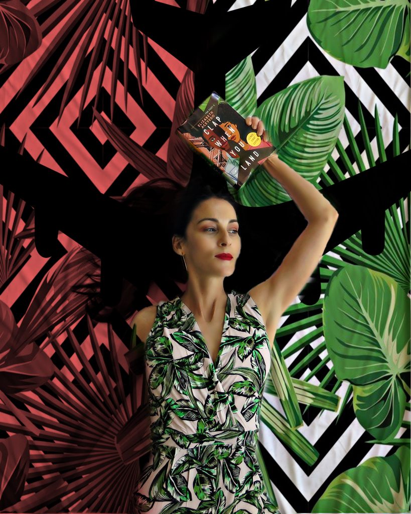 Carmen in front of a red, white, and green background with palmetto leaves while heading a book over her head