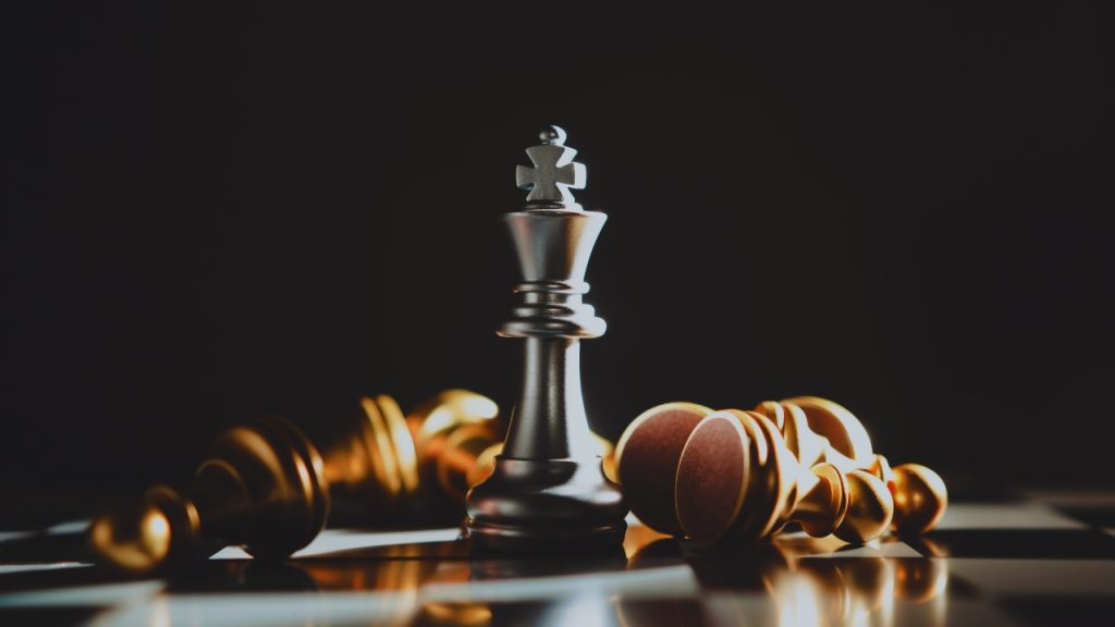 Chess board with only the king standing. Pawns and other pieces lay on their sides around it.