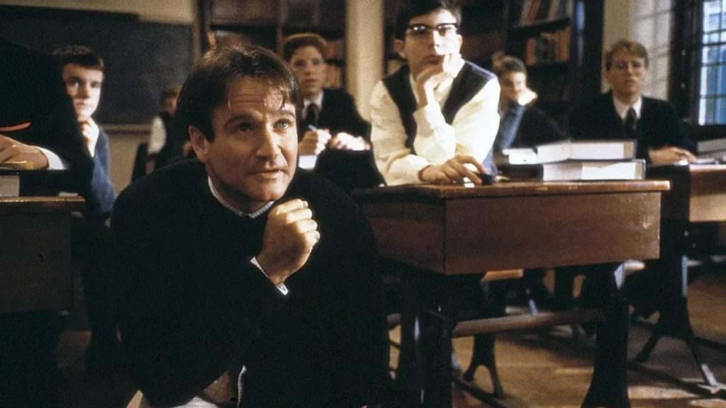 "Dead Poets Society" scene of the movie with Robin William's John Keating in a classroom, kneeling as he looks at something ahead as the rest of his students.