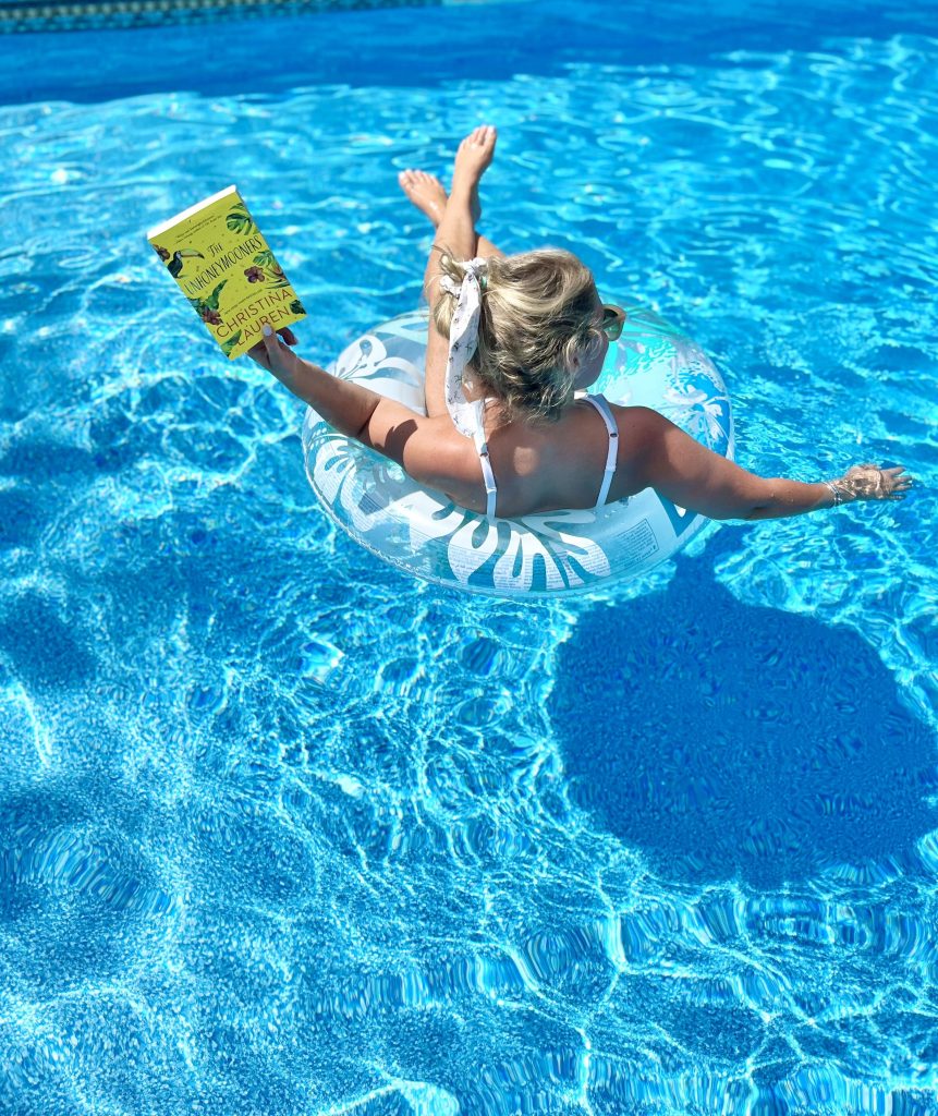 Michelle sitting in a pool with a book in her hand.