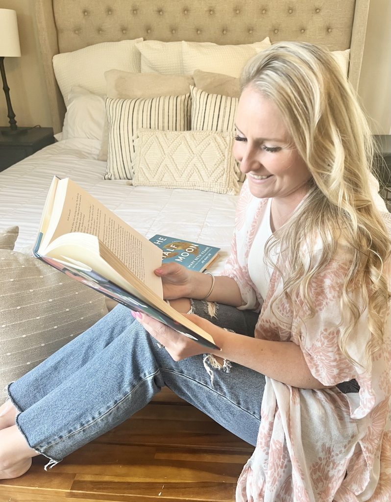 Michelle sitting on the floor smiling with a book in her hands.