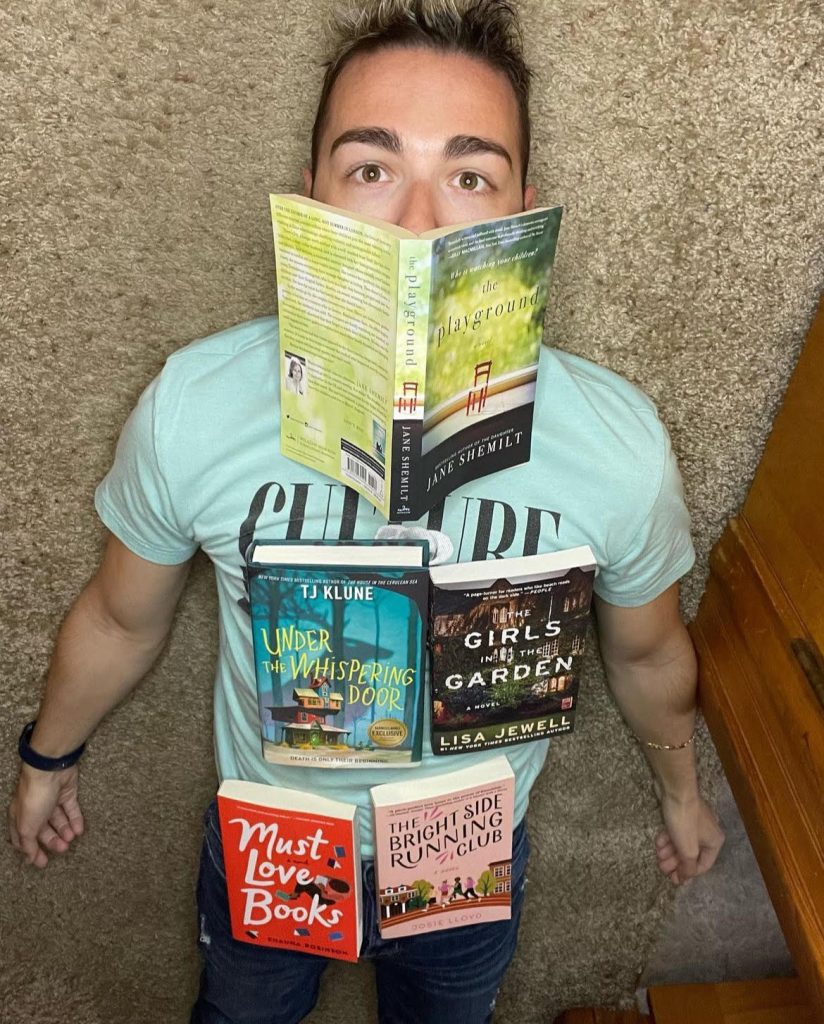 Image of Bookstagrammer Frank DiLuzio lying on his carpeted floor with books covering his body.
