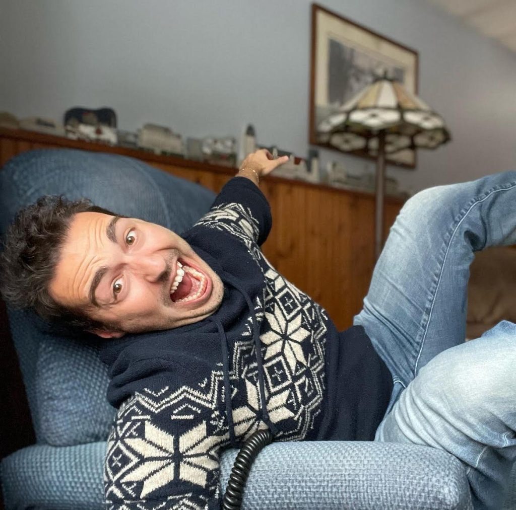 Image of Bookstagrammer Frank DiLuzio sprawled on his blue, corduroy recliner, his legs in the air and his facial expression resembling an ecstatic scream.