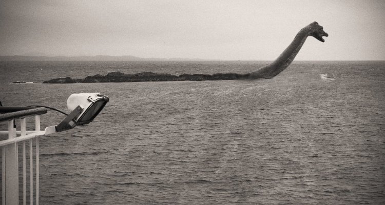 A photo in greyscale of a giant and prehistoric snake-like creature floating in the sea.
