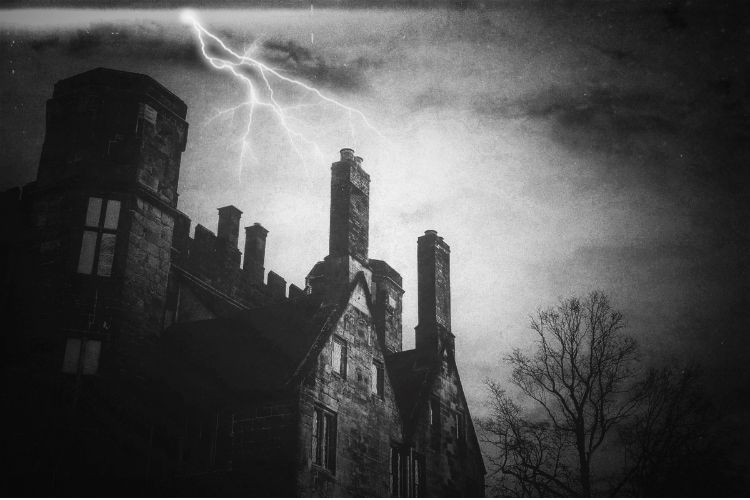 Gothic castle in black and white with lightning striking above.