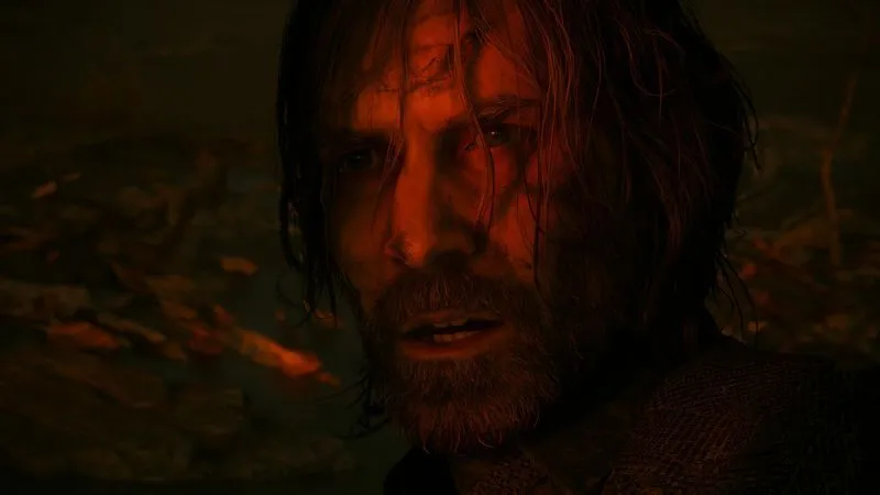 Alan Wake with a distraught expression, illuminated by a red light against a dark forest background.