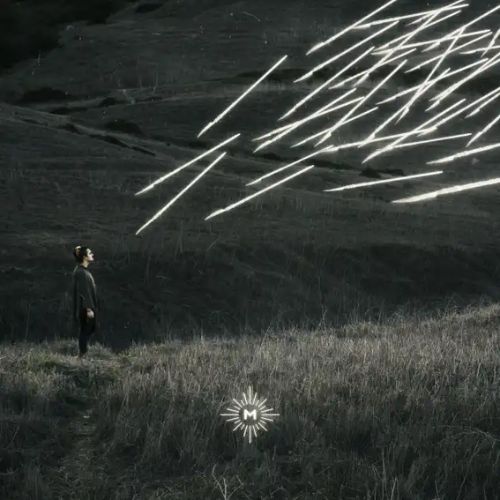 Nocturne by Saint Mesa album cover. The side profile of a man with dark hair stands in a field with rolling hills behind him. He looks up at a great amount of lines of glowing light, potentially intended to be knives or arrows, approaching him. In the bottom center of the image, an M is surrounded by glowing light lines.