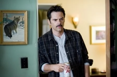 Charlie Swan leading against the doorway as he holds on to a beer.