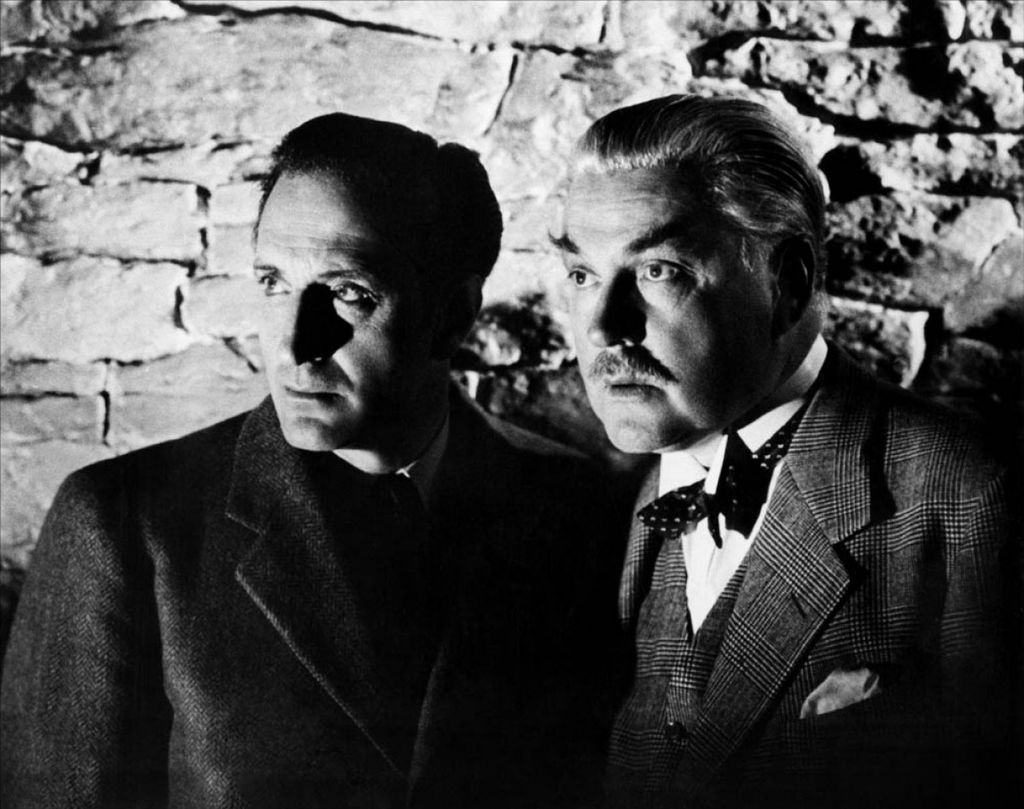 Black and white image of Sherlock Holmes and John Watson from 'Sherlock Holmes and the Secret Weapon' staring at something off camera.