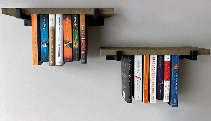 Upside down books on a wooden shelf.