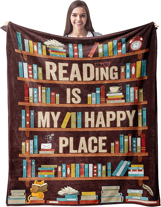 A girl holding open a plushie blanket showing a bookshelf, a pile of books, and the phrase "reading is my happy place."