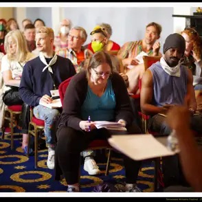 A group of people sitting during a writing conference in a large room.