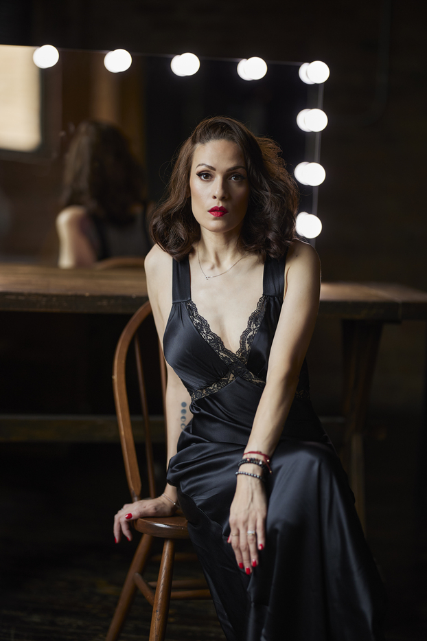Author Cynthia Pelayo in black dress in front of mirror.