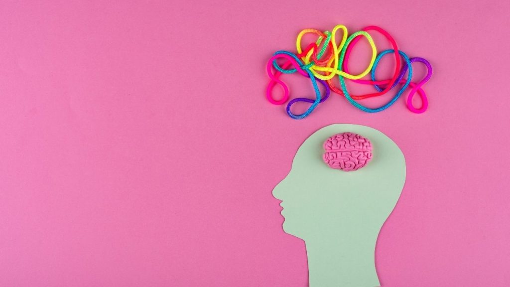 The background is pink. A silhouette of a face with a pink brain. Above it are colorful swirls.