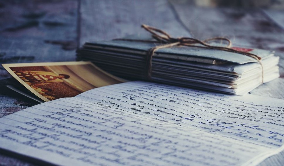 A handwritten letter next to a photo and a stack of letters