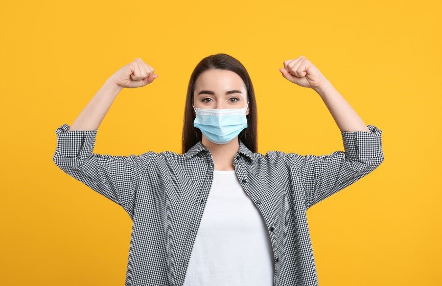 A woman wearing a mask with her arms lifted