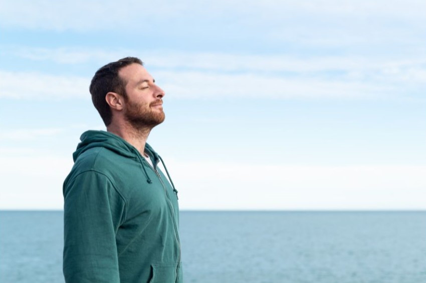 A man standing near the ocean and smiling