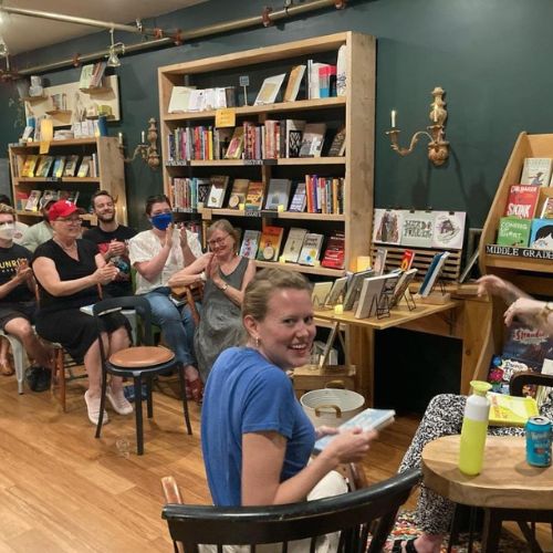 Kate Doyle holding her book in an author signings and talk in a bookstore.