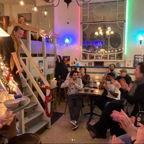 Kate standing on stairs talking to a group of readers in a cafe