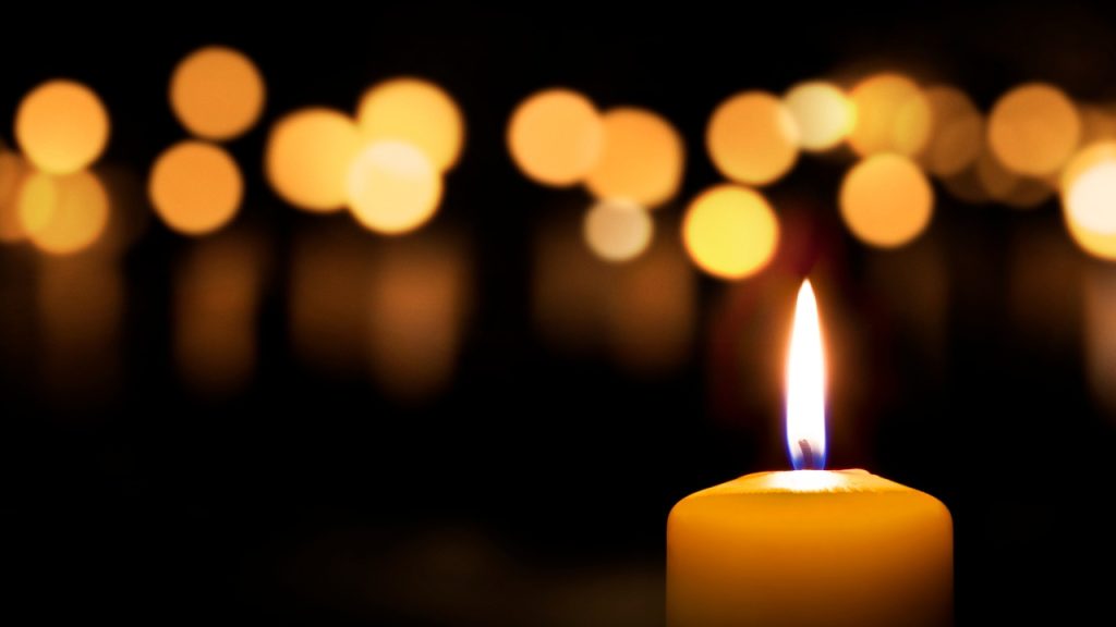 Lit candle on a background of blurred lights.