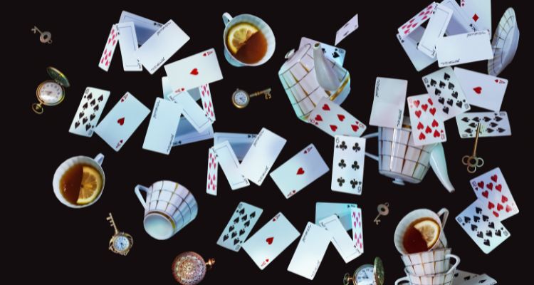 The background is black. Playing cards, teacups, and watches are flying in mid-air.