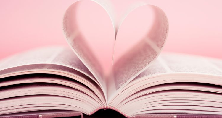The background is pink. A book is unfurled with 2 pages, creating the shape of a heart.