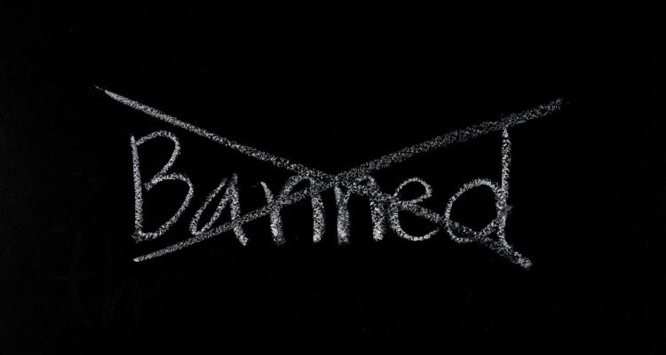 The background is black. The word "Banned" has been crossed out in white chalk.