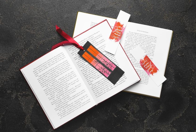 Two open books overlapping each other with three bookmarks on them