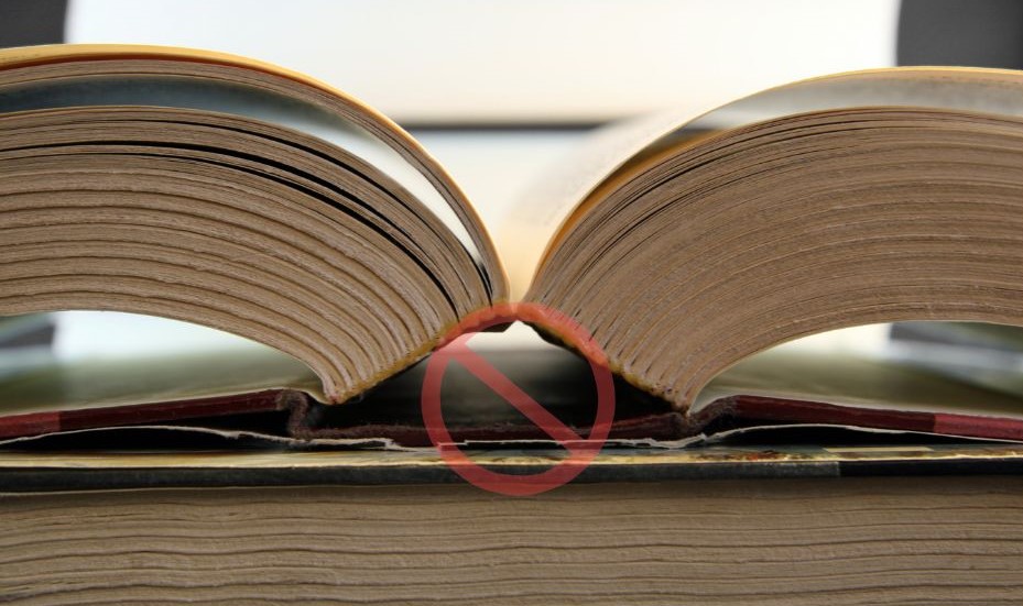 A book with a cracked spine and a no symbol in front of it