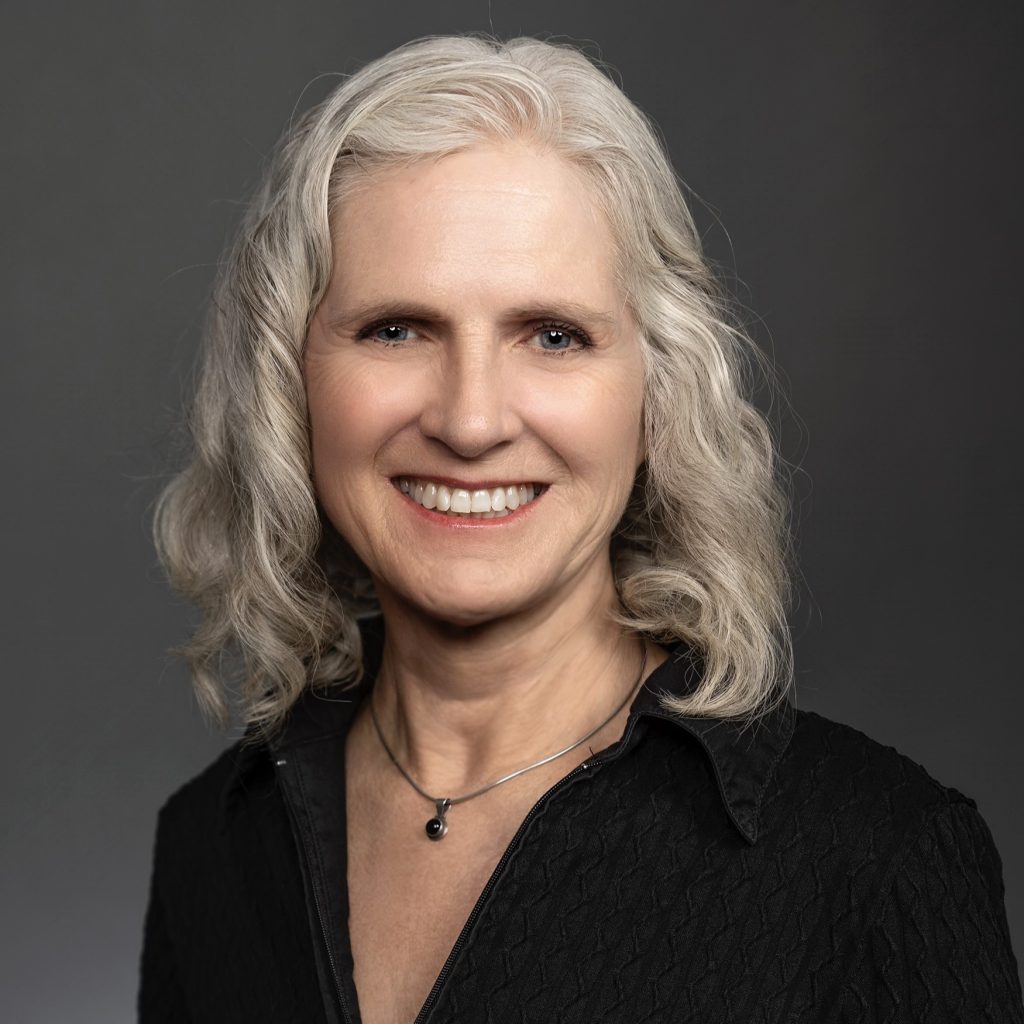 Author Natasha Wing, a smiling white woman with white hair wearing a black blouse in front of a gray background.