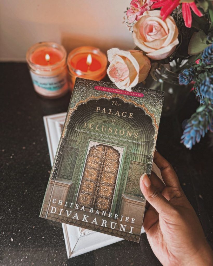 Image provided by @iambibliomane of the book "The Palace of Illusions" by Chitra Banerjee Divakaruni of a green building with a brown decorative door.