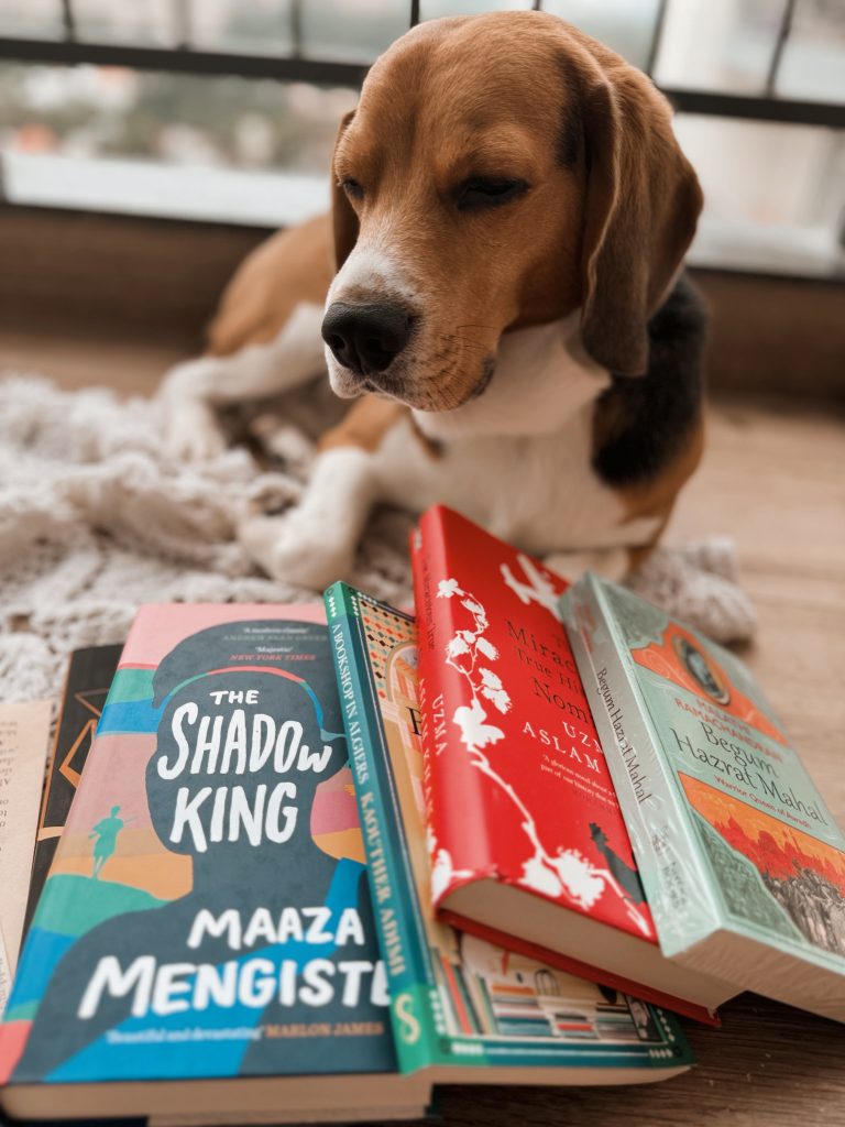 Image by @iambibliomane of her dog Pablo lying behind a pile of books on the floor.