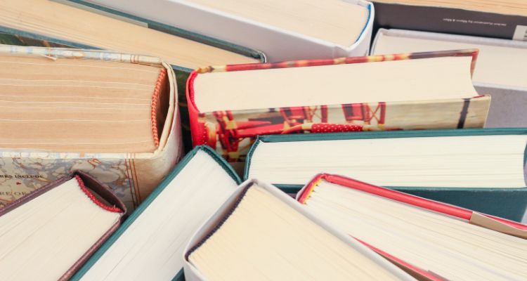 A close-up view of several books arranged with their spines and pages visible, showcasing a variety of colors, textures, and bindings.