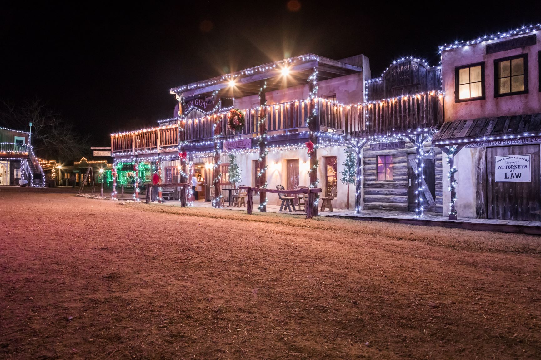 A Wild West–themed building decked out in white string lights and Christmas wreaths with red bows.