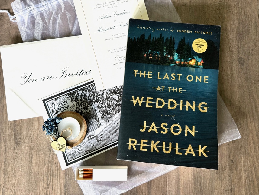 A wooden table top with a collection of items that include a book, a box of matches, a postcard, and an envelope.