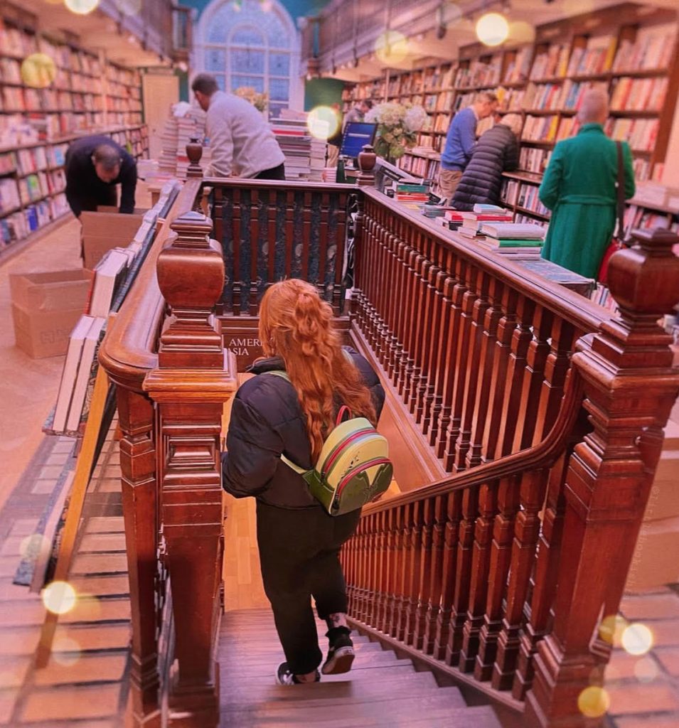 Lauren walking down the wooden stairs of a bookstore.