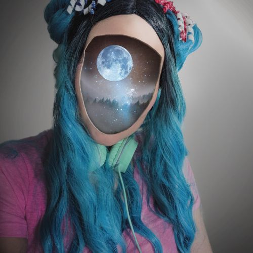 Beatrix Hollow with blue hair in a pink shirt and mint green headphones around her neck. Her face has been replaced by a nighttime scene with the moon, stars, and a foggy forest.