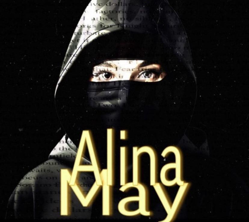Alina May on a black background. She is wearing a black hood and a black face mask. Only her eyes are visible.