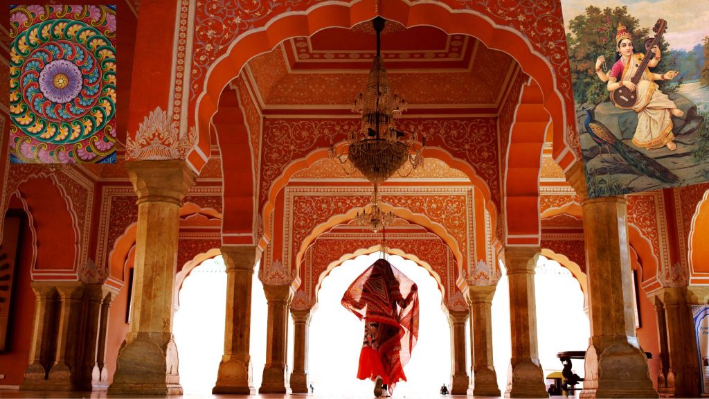 A lady walking in an Indian temple, with paintings/murals in either corner.